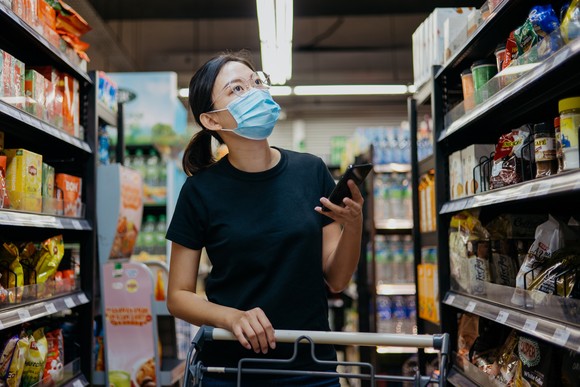 A masked person shopping in a supermarket.