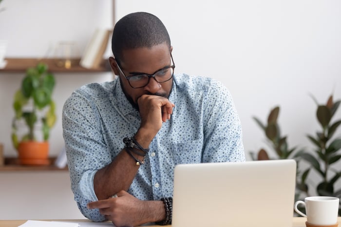 Person looking at a laptop and feeling worried.