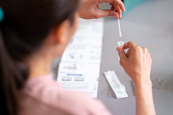 Person placing a swab sample into a container.