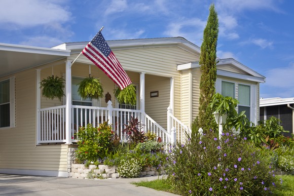 Mobile home with American flag hanging off porch.