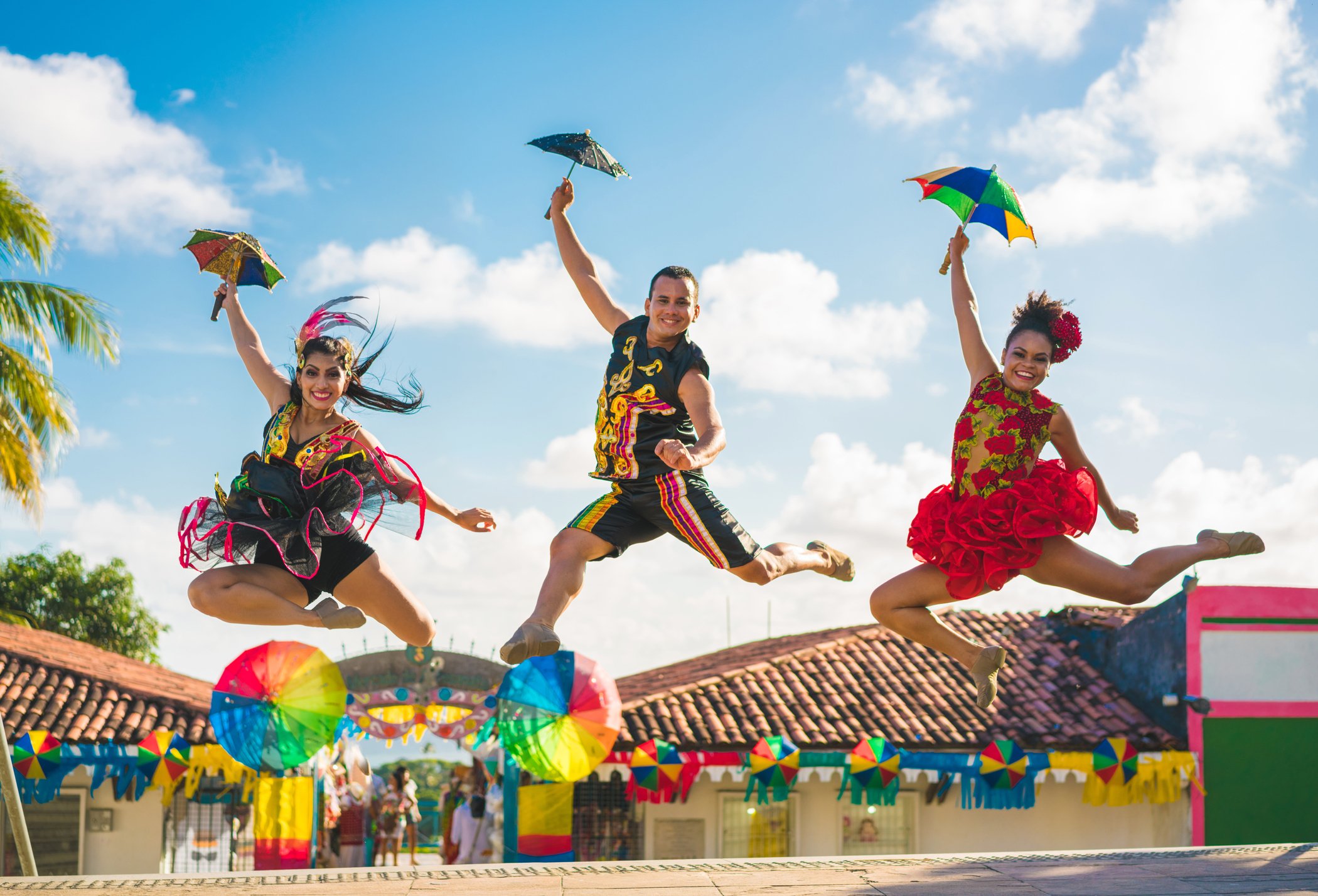 Three dancers jumping in Brazilian costumes.