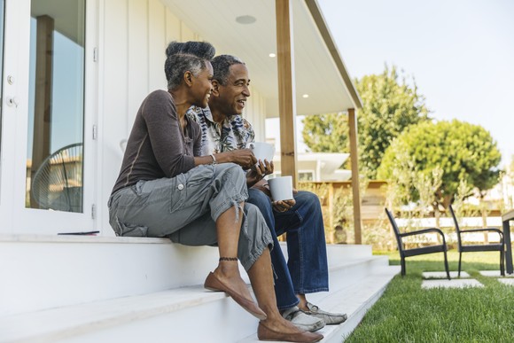 A retired couple sitting on their porch steps. 