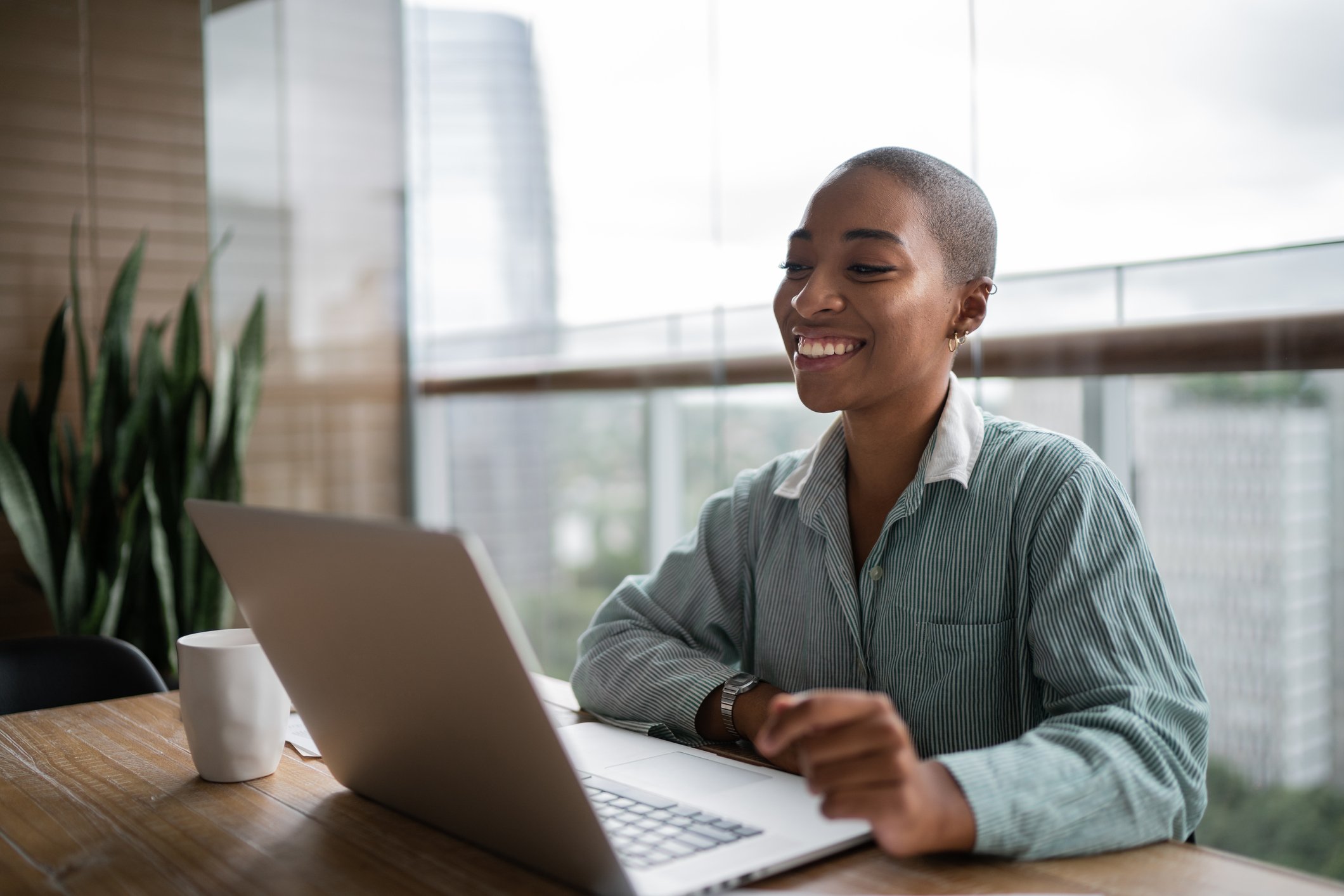A person smiling and working on a laptop computer.