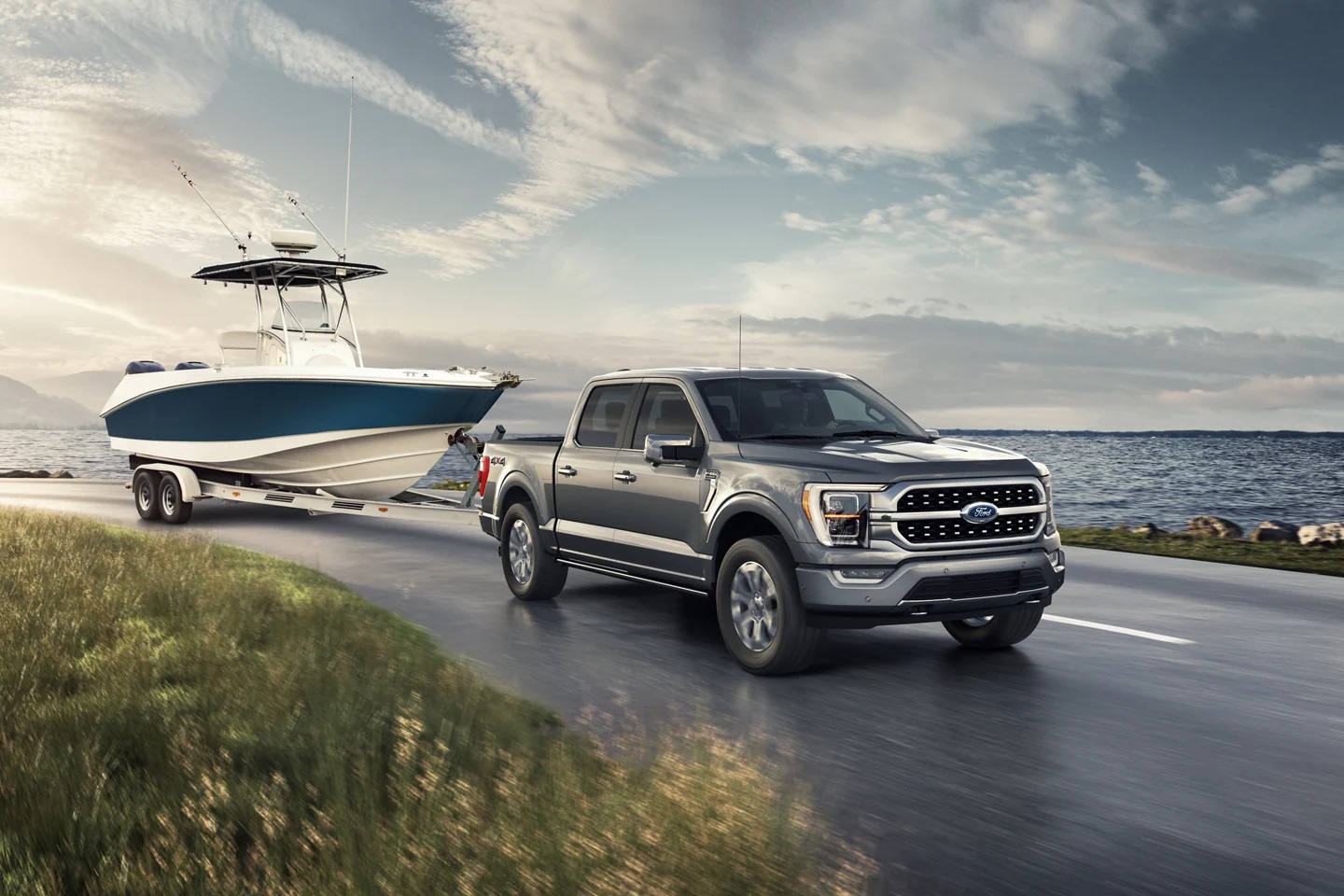 A gray 2021 Ford F-150 Platinum truck pulling a boat next to a body of water.