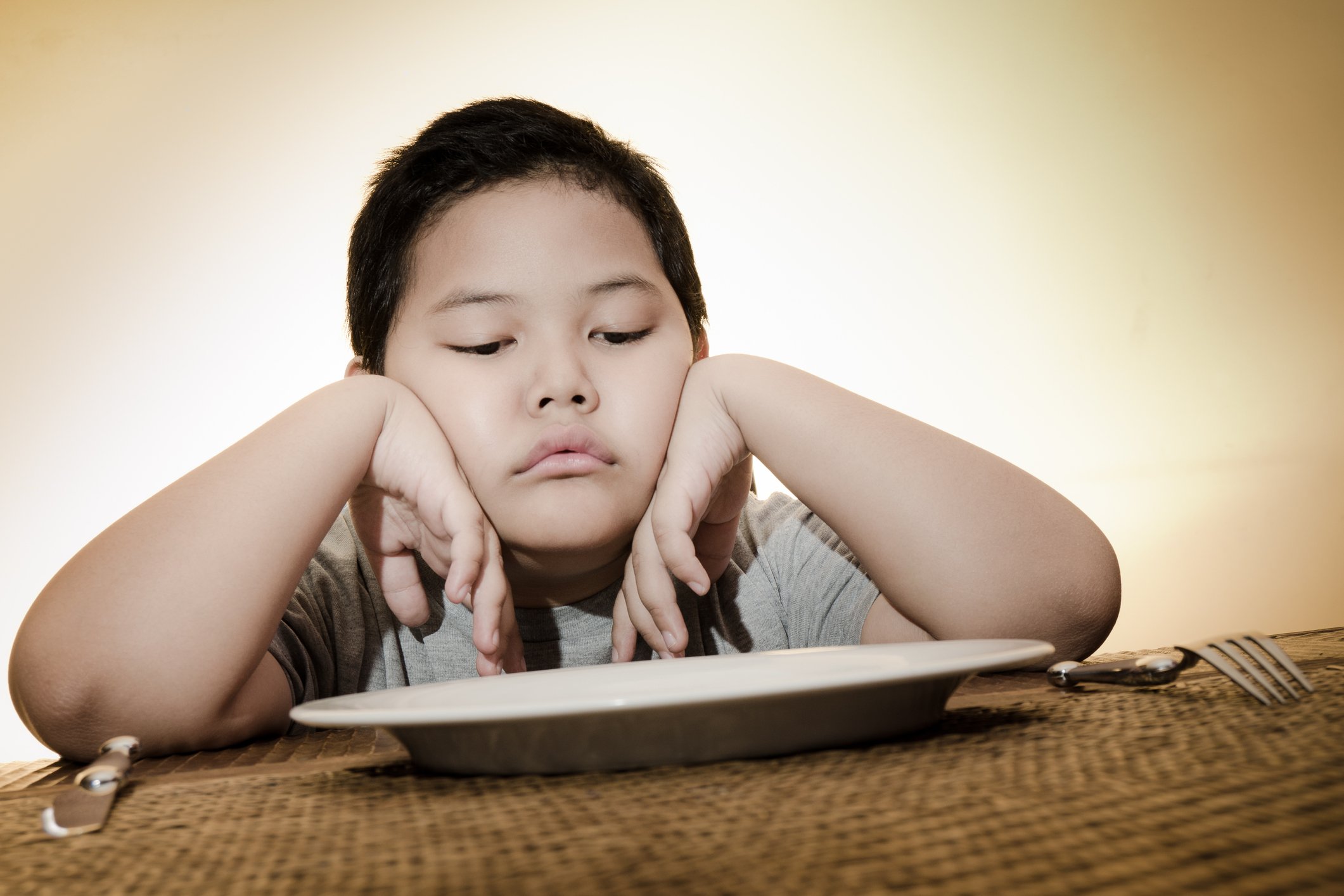 Child gazing at an empty plate.