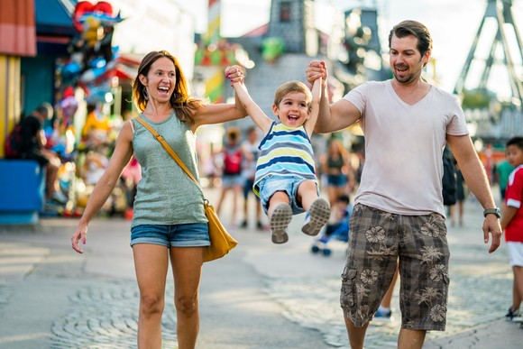Two adults and child enjoying a trip to a theme park.