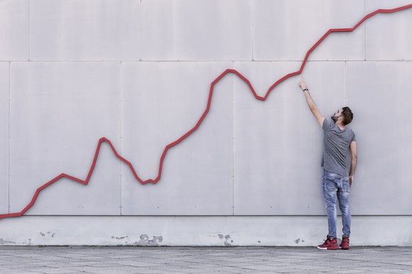 A person pointing to a chart that is going upward.
