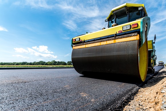 A steamroller flattening an asphalt road.