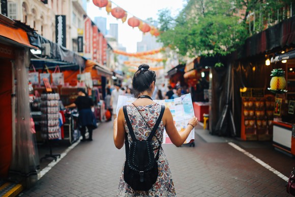 A tourist holding a map while walking in a city.