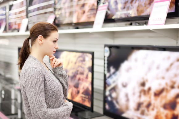 Person browsing TVs at a retail store.