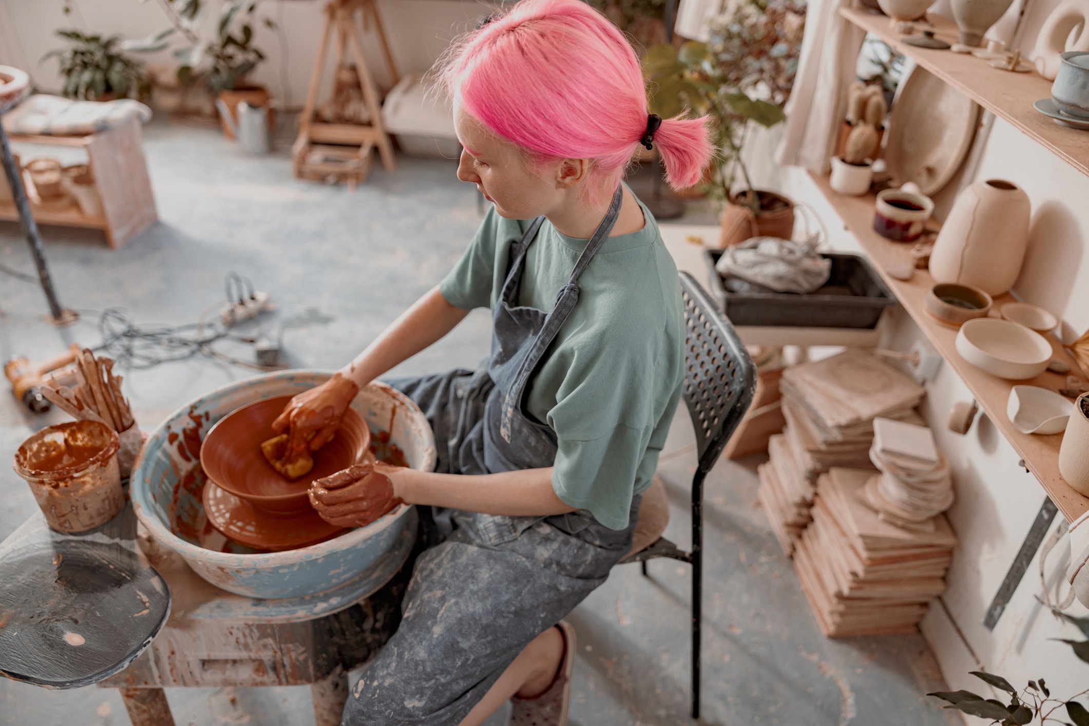 Person in a studio using a pottery wheel to make a bowl.