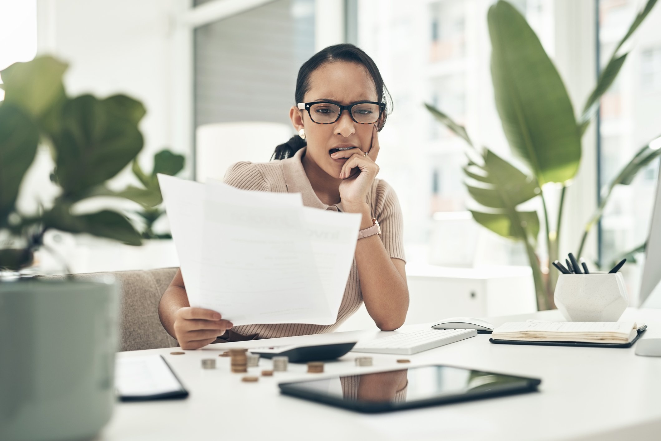Person sitting at a desk and looking anxiously at paperwork.