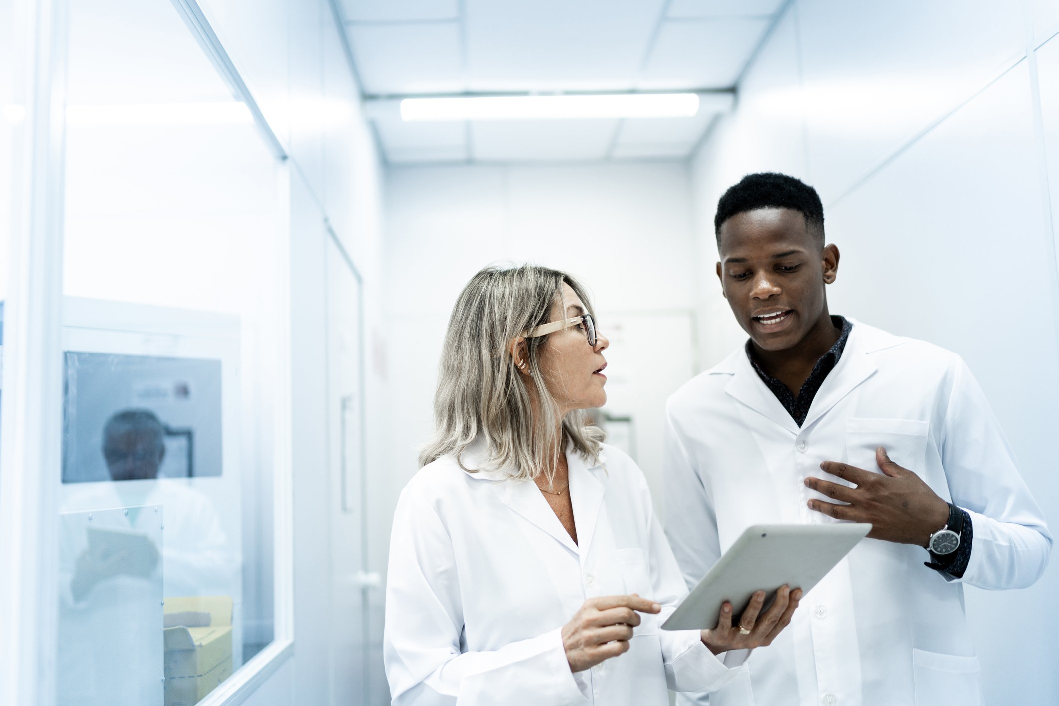 Two colleagues look at a tablet in a lab.