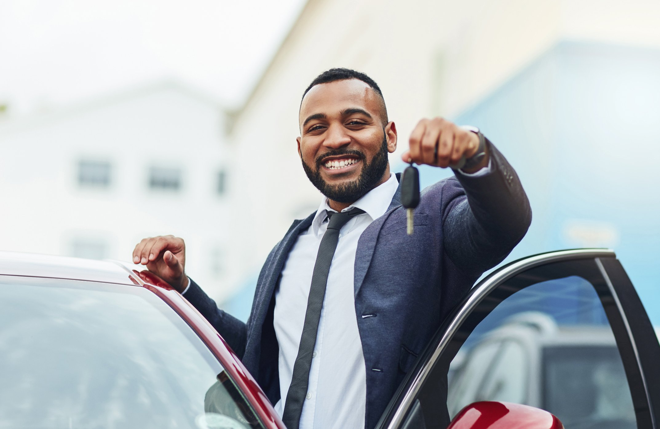 Person holding car key next to car with door open.