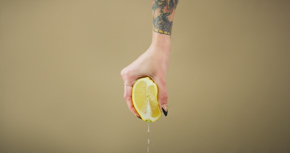 A person's hand squeezing a lemon.