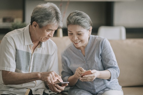 Two smiling people looking at smartphones.