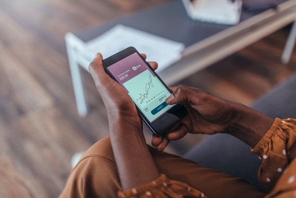 Woman looking at a stock chart on a smartphone.