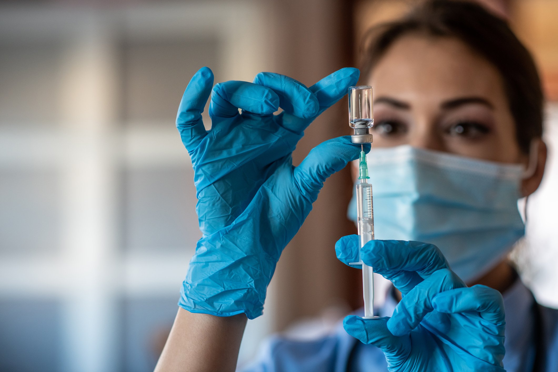 A healthcare worker draws up a dose of vaccine in a syringe. 