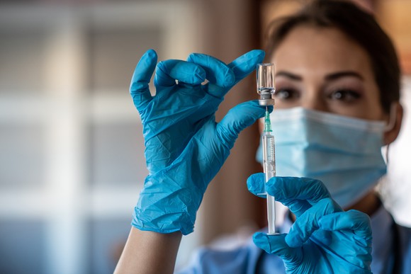 A healthcare worker draws up a dose of vaccine in a syringe. 
