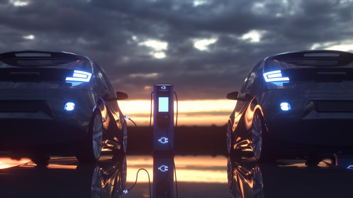 Rear view of two electric cars charging at sunset.
