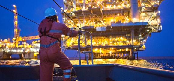 Worker at illuminated offshore oil rig.