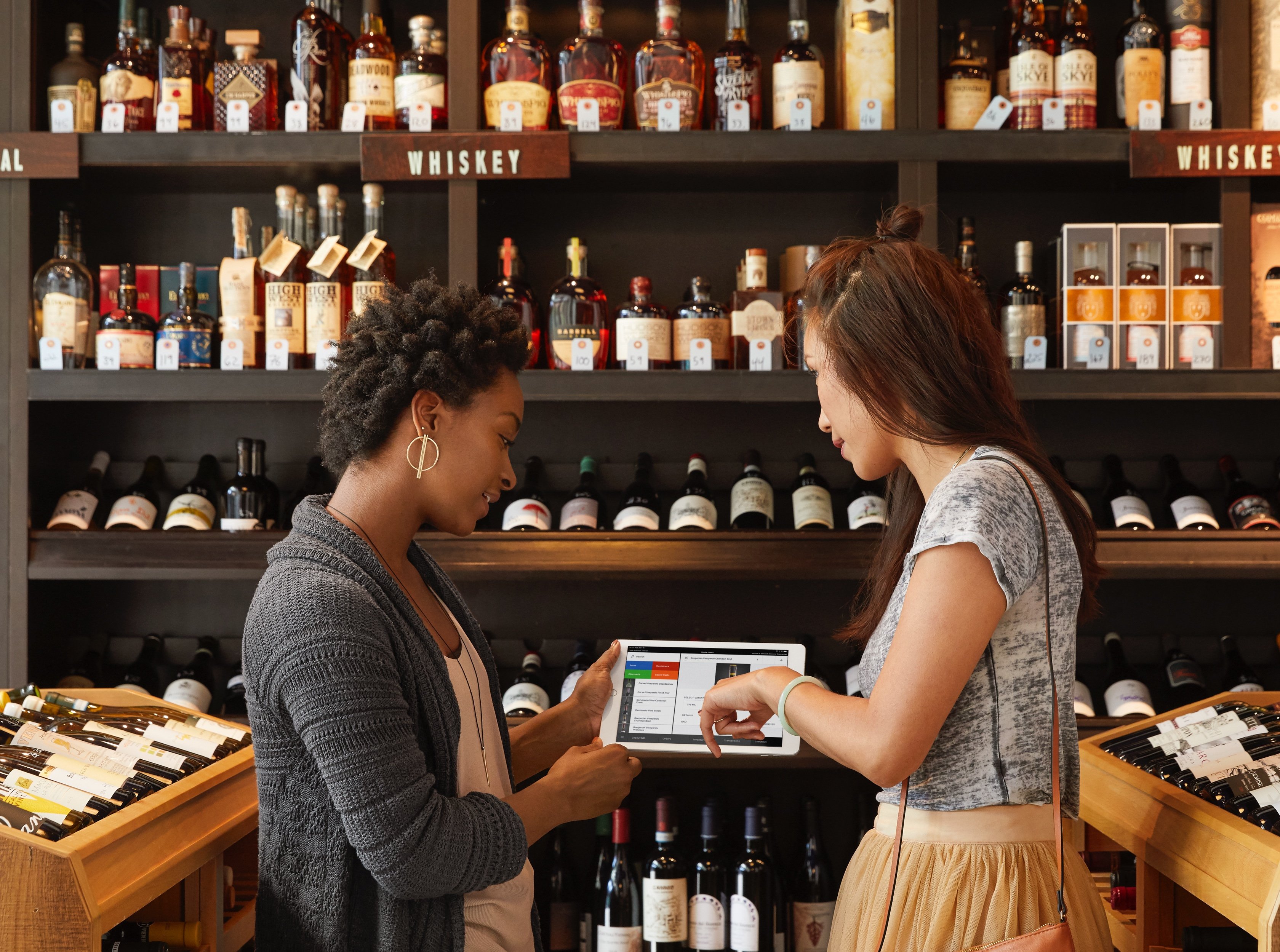 Two people in a wine shop using a tablet computer.