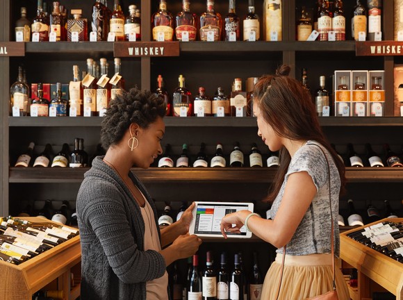 Two people in a wine shop using a tablet computer.