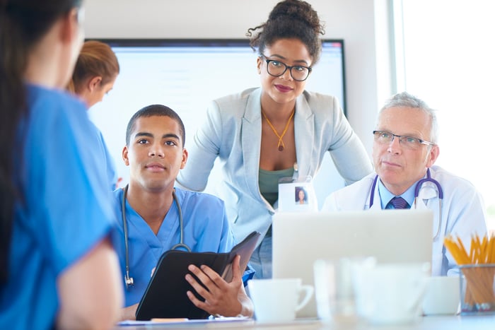Medical professionals have a discussion around a table in a conference room.