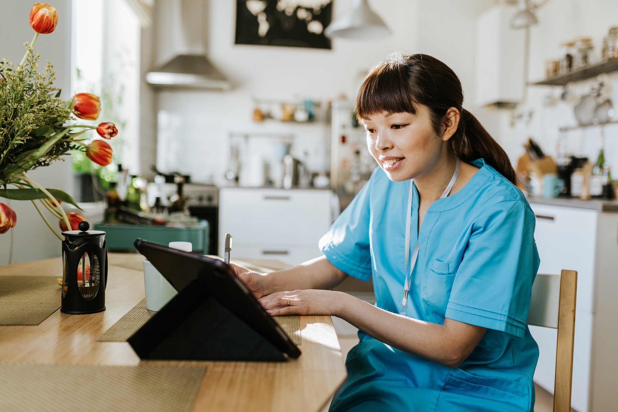 A doctor sitting in her kitchen does a telehealth visit with a patient.