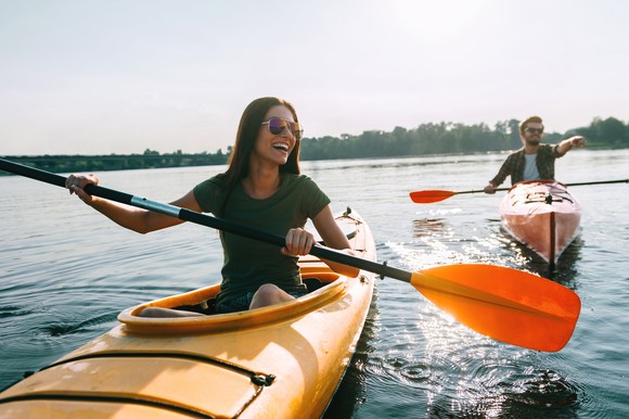 Two people in kayaks in the summertime. 