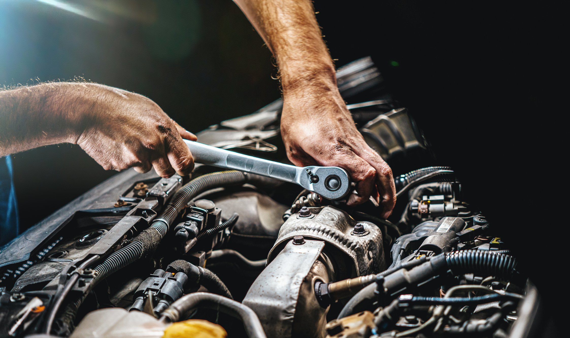A mechanic using a torque wrench on a car's engine.