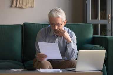 Old person with laptop reading papers