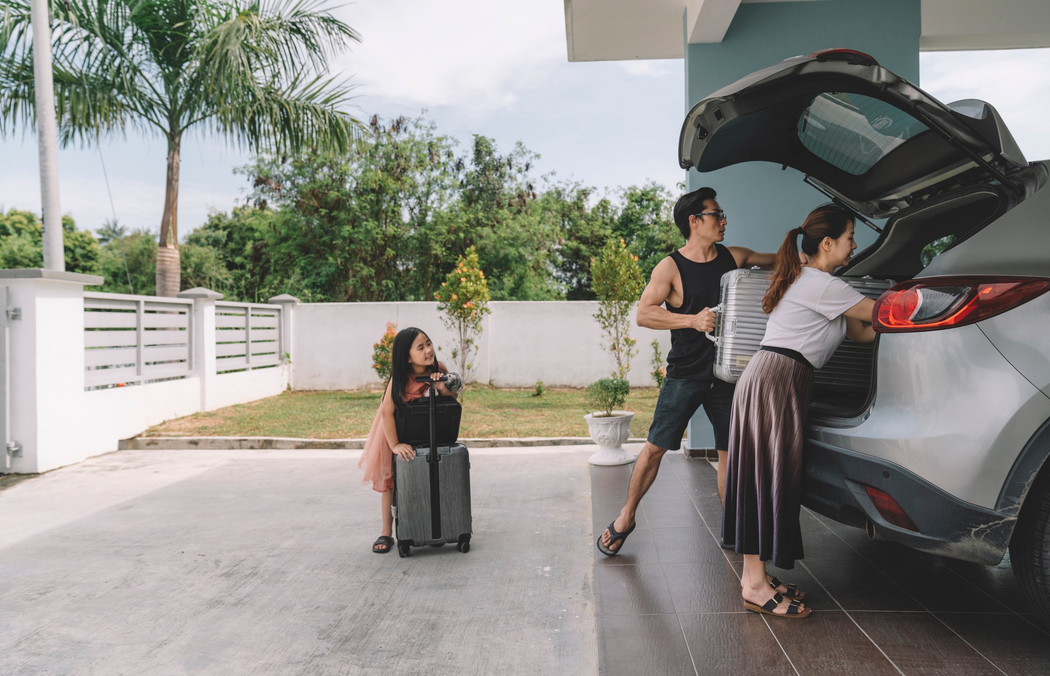 Adults and child putting luggage in the car.