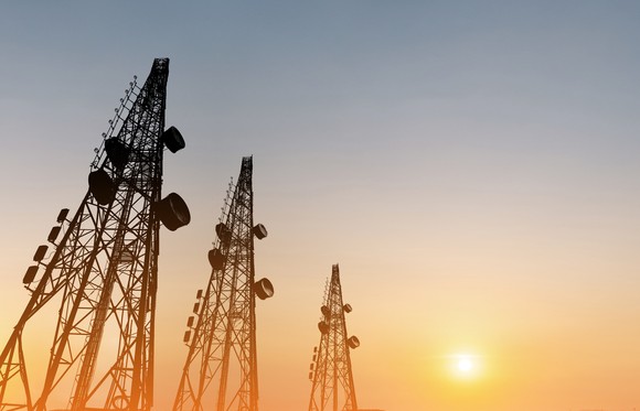 Three telecom towers silhouetted against the sky.