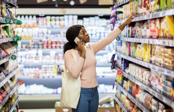 A grocery shopper reaching for an item on the shelf.