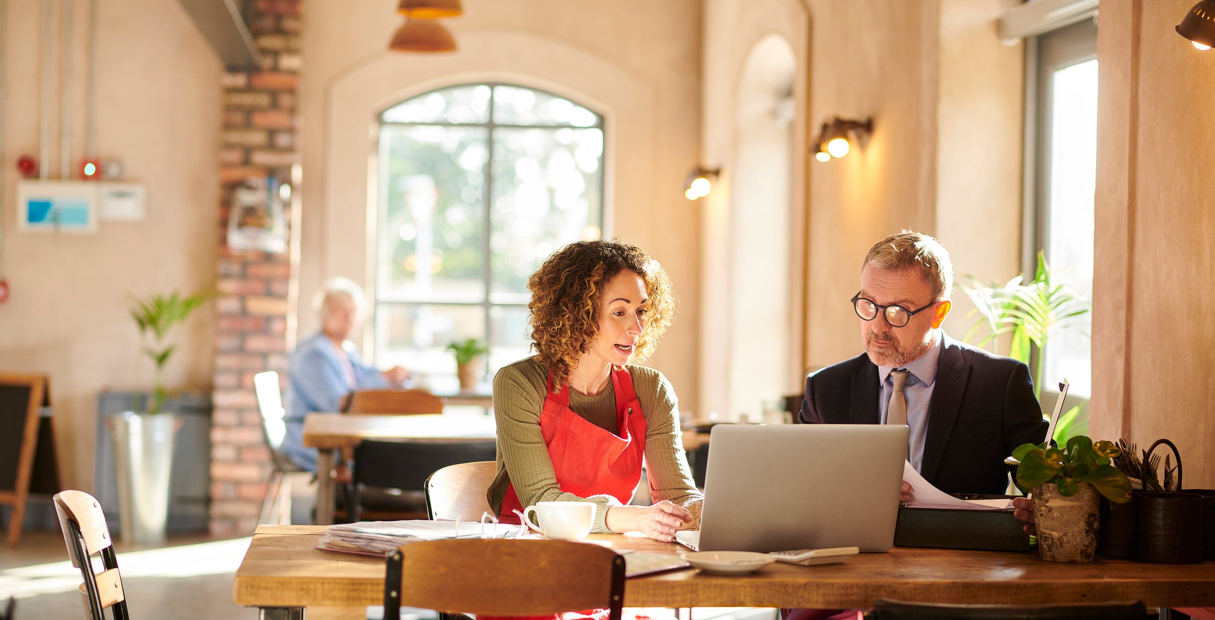 A small business owner talks to a banker in a coffee shop.