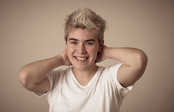 A young adult is smiling and looking at the camera.