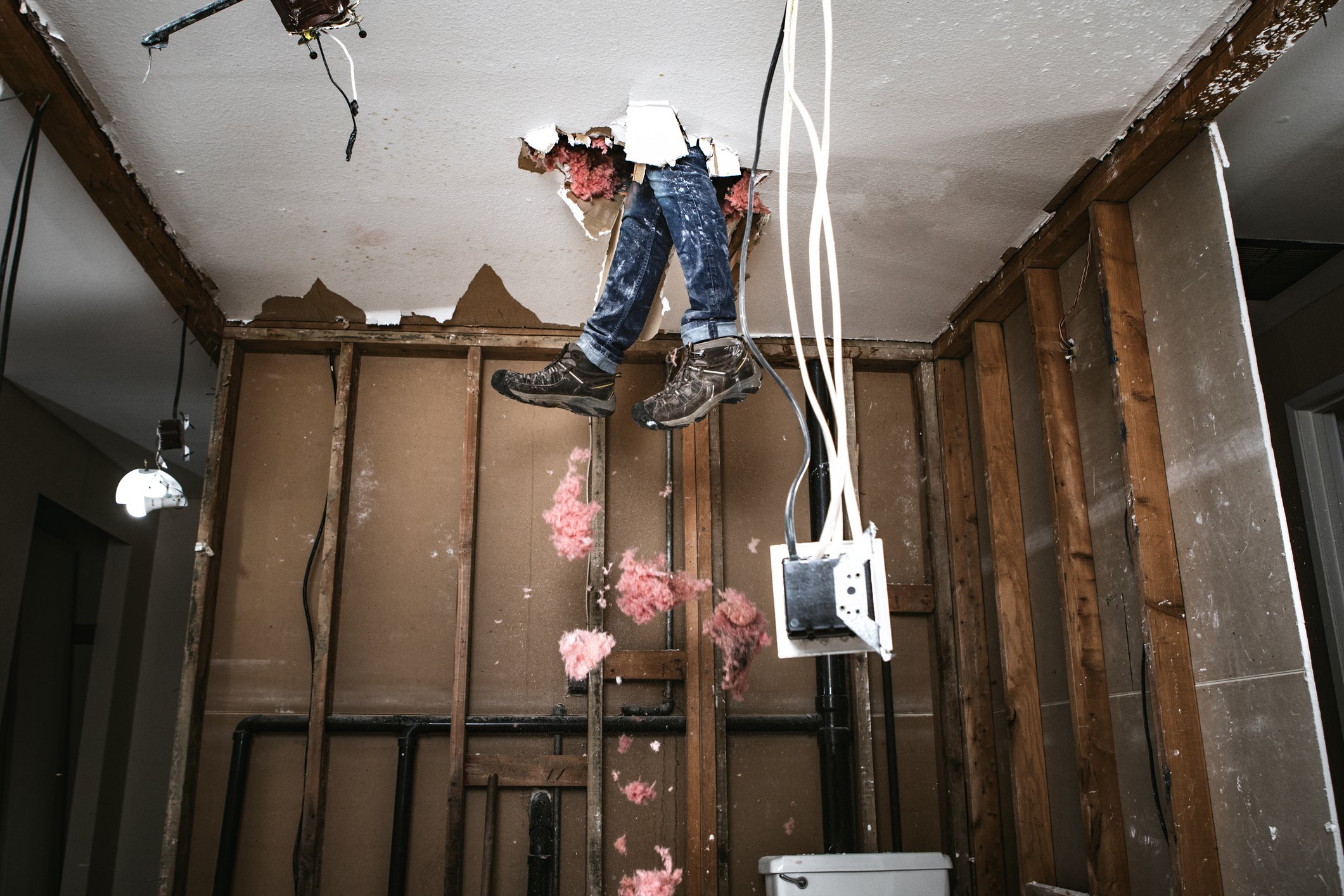 A pair of legs have broken through the ceiling of a rundown home.