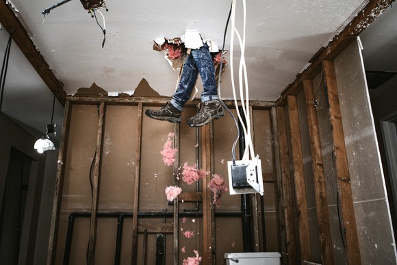 A pair of legs have broken through the ceiling of a rundown home.