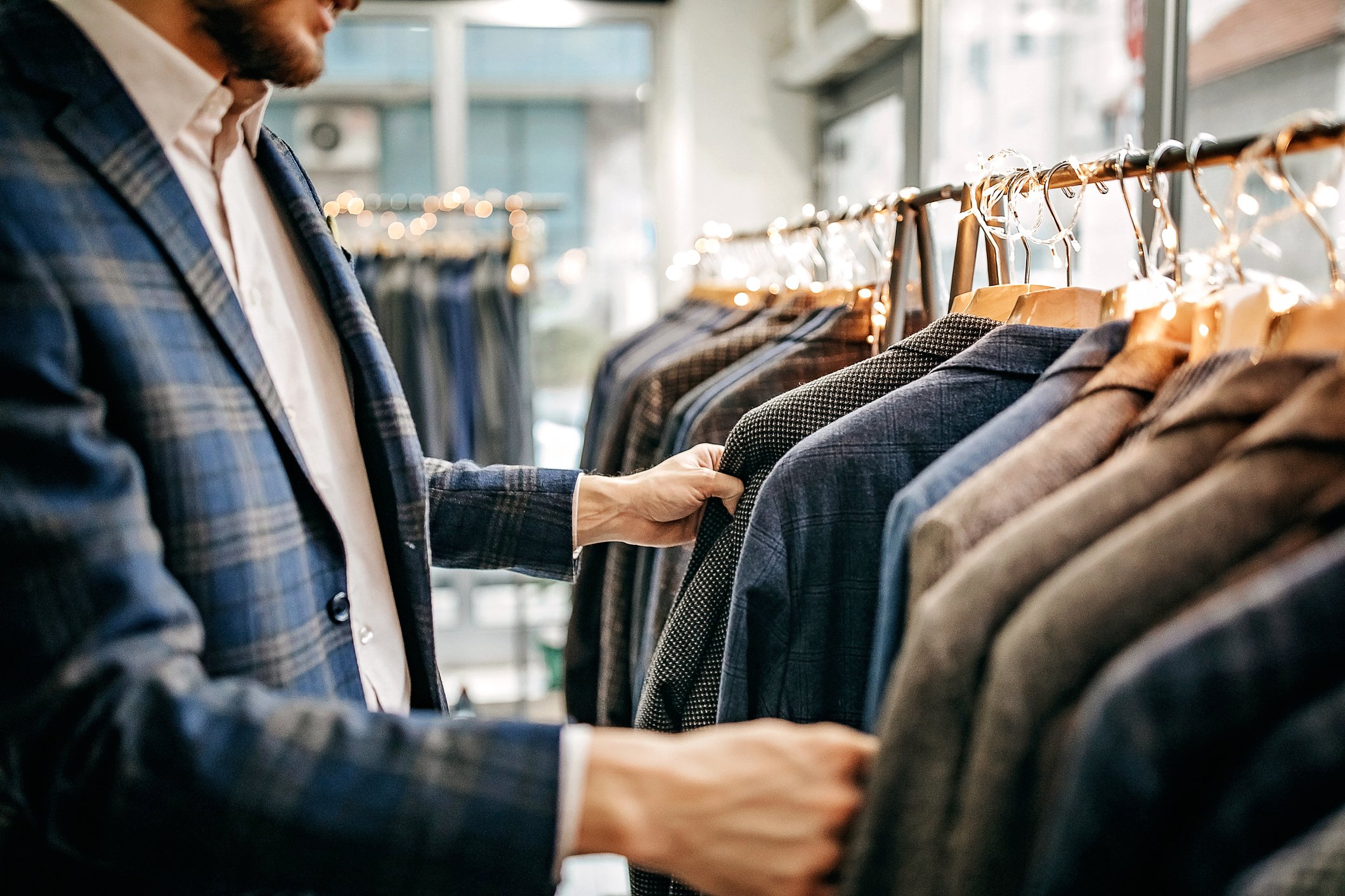 A man checking suits on a suit rack.