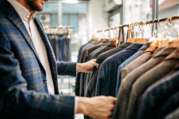 A man checking suits on a suit rack.