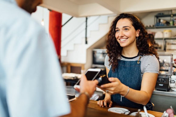 Person making contactless payment in coffee shop.