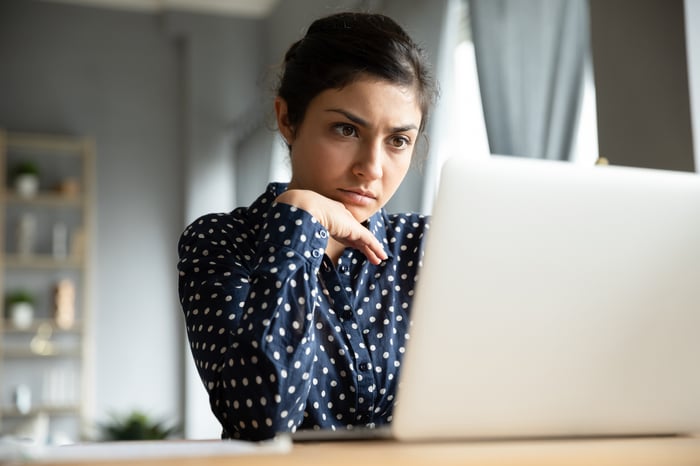 Person sitting at a desk looking at a laptop.