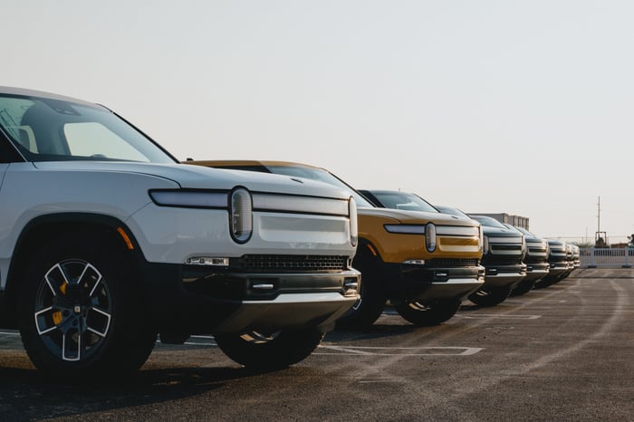 Rivian trucks lined up in parking lot. 