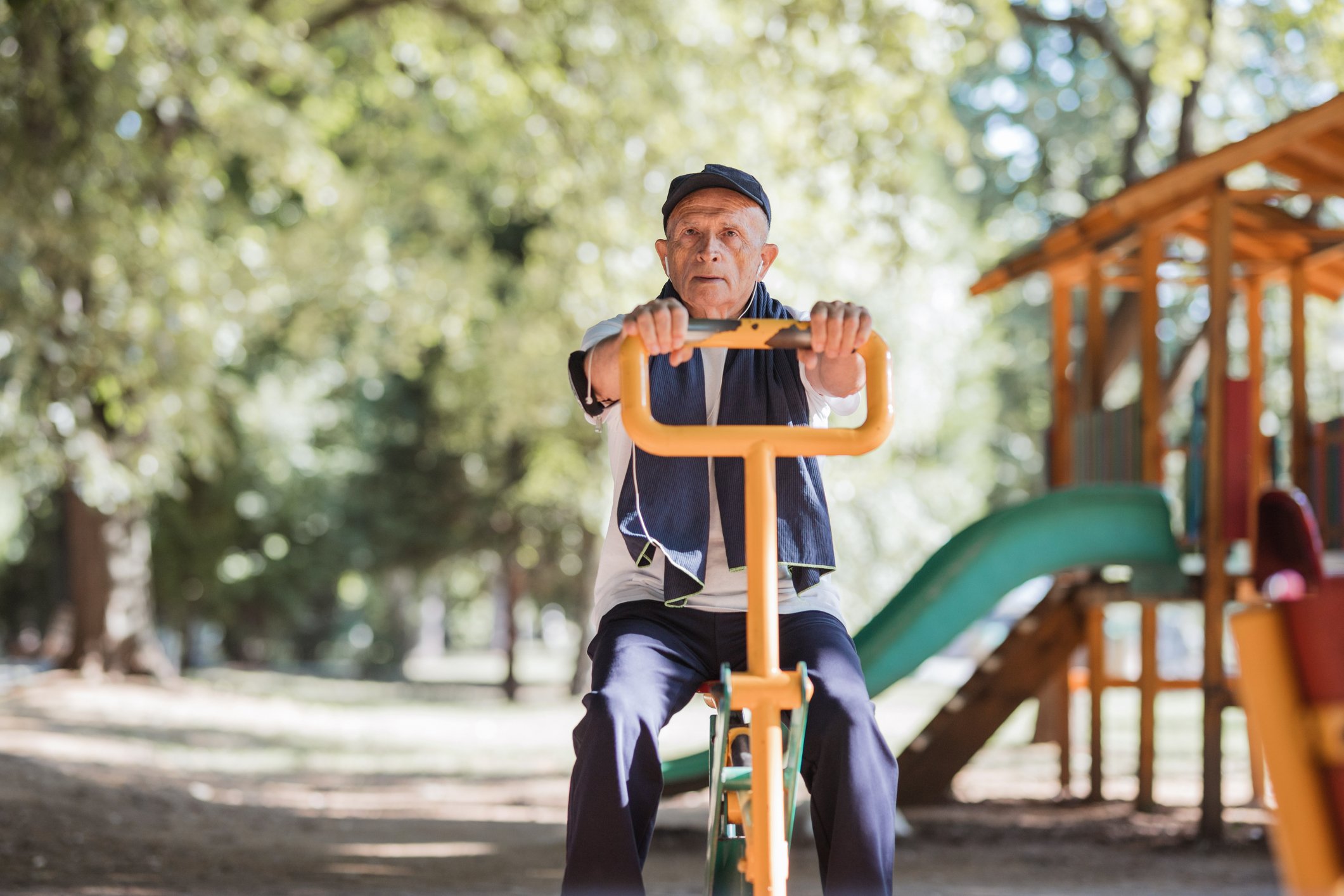 A senior citizens holds on to an object at a public playground.