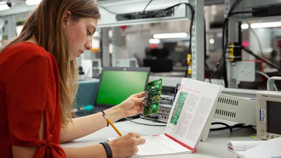 Person examining computer circuit board.