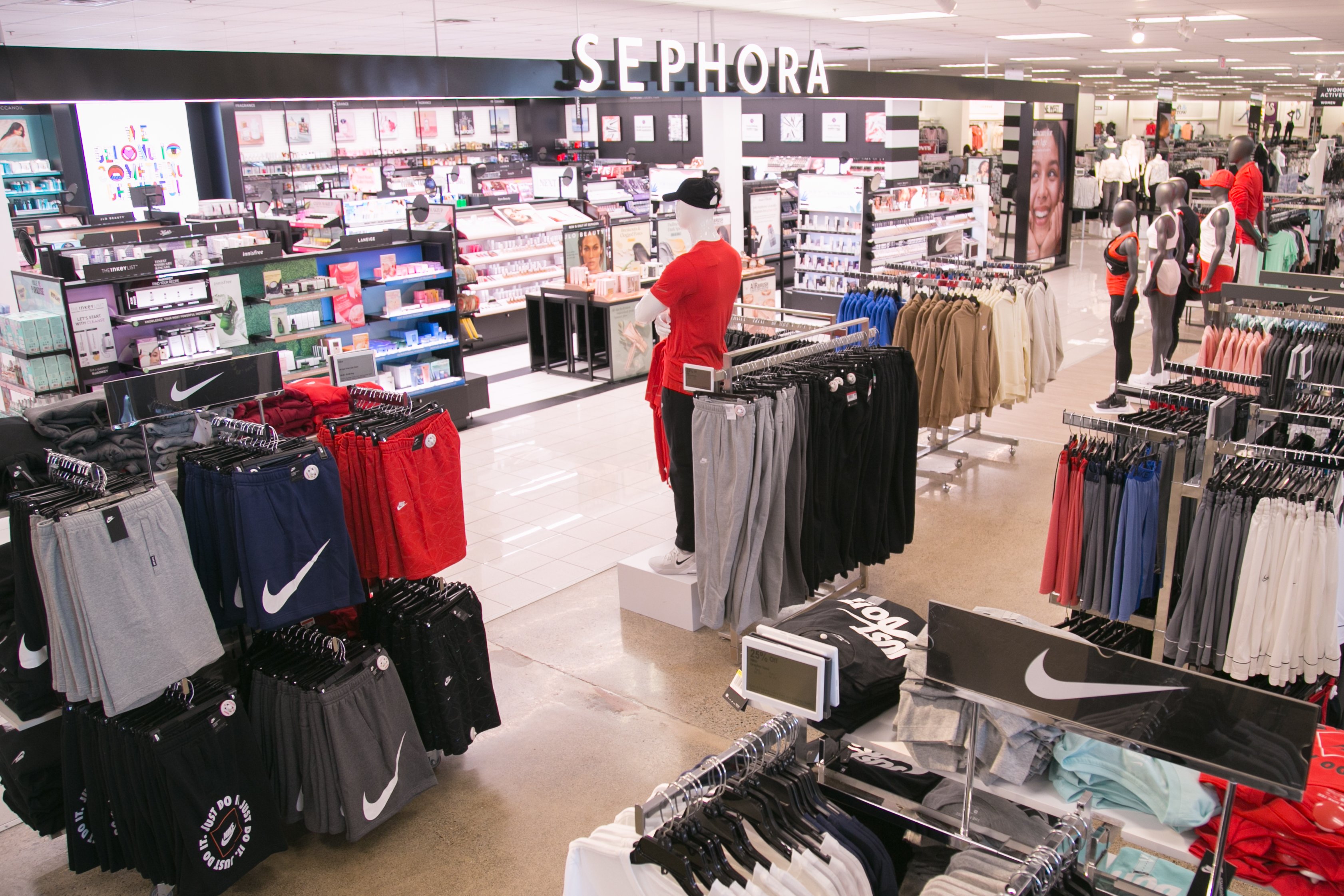 Racks of apparel in a Kohl's store, with the Sephora shop in the background.