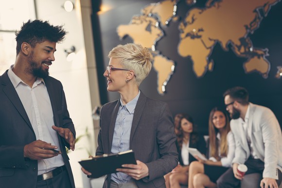 Diverse group of businesspeople in front of a map of the globe. 