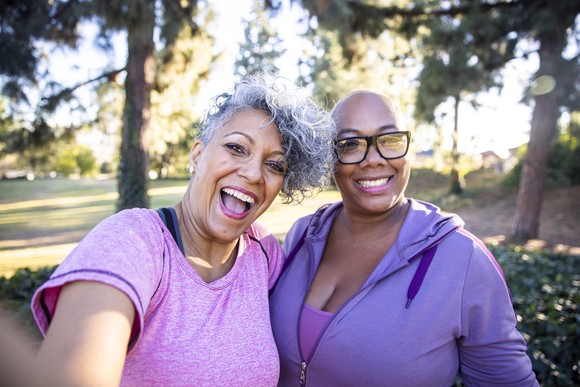 Two smiling people take a selfie outside.