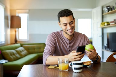 person looking at phone and eating apple